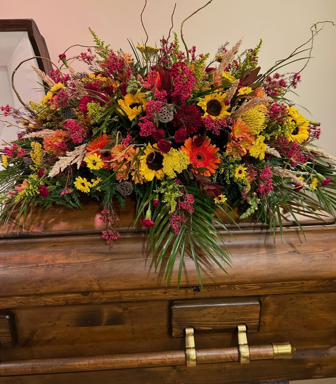 Sunflower and fall-toned casket spray sympathy arrangement