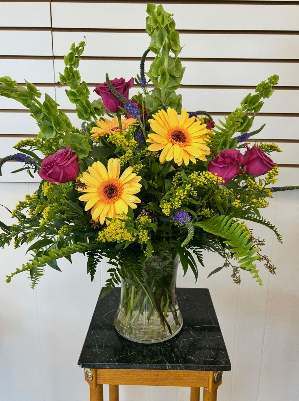 Fresh vase arrangement with gerbera daisies, roses, and bells of Ireland from Village Gallery Florist
